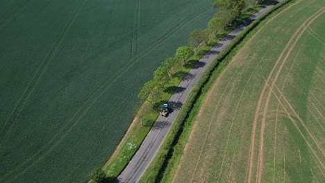 Toma-Aérea-De-Un-Pequeño-Tractor-Azul-Conduciendo-Por-La-Carretera