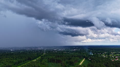a slow aerial drone shot descends over a dense pine forest, revealing the town of engure, latvia, under a dramatic and moody sky filled with dark storm clouds