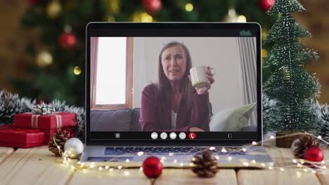 feliz mujer mayor caucásica en videollamada en computadora portátil, con decoraciones de navidad y árbol
