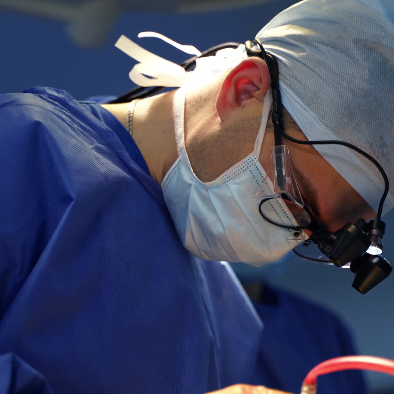 Facial portrait of a doctor. Surgeon in medical uniform and mask performing an operation. Profile view. Close-up
