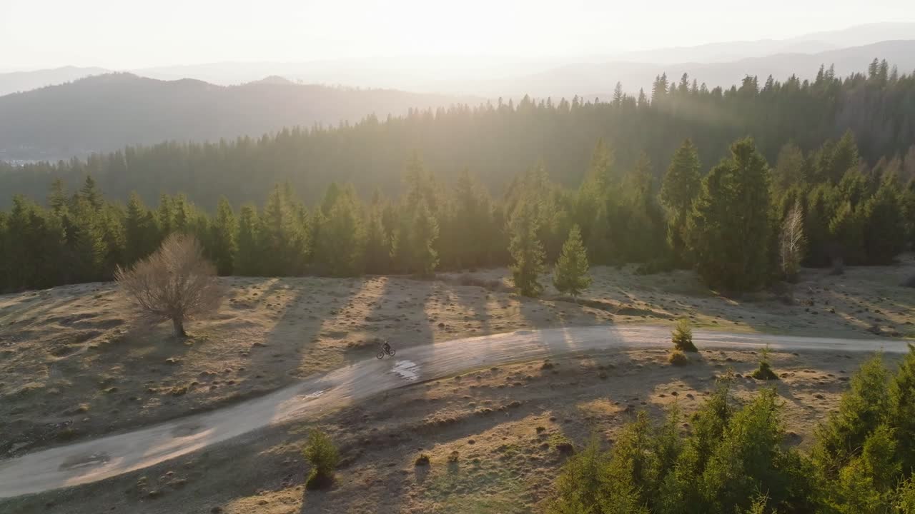 un ciclista viaja a través de un sendero de montaña boscoso al atardecer con largas sombras y luz dorada