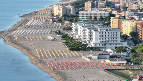toma aérea a 30 fps de una playa de arena con paraguas, típica costa adriática