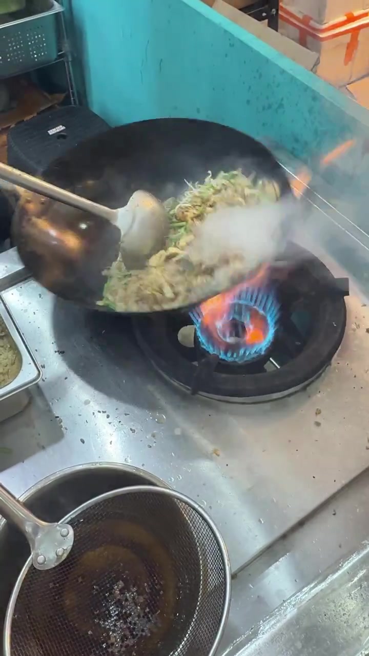Chef che salta le verdure in un wok a fuoco vivo