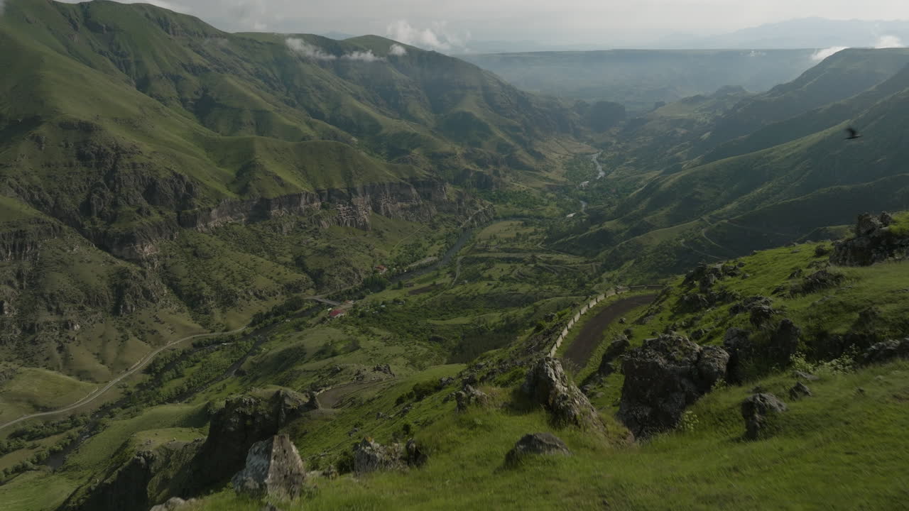 Volando sopra una montagna verde che rivela una strada di montagna e il fiume Mtkvari vicino a Borjomi in Georgia