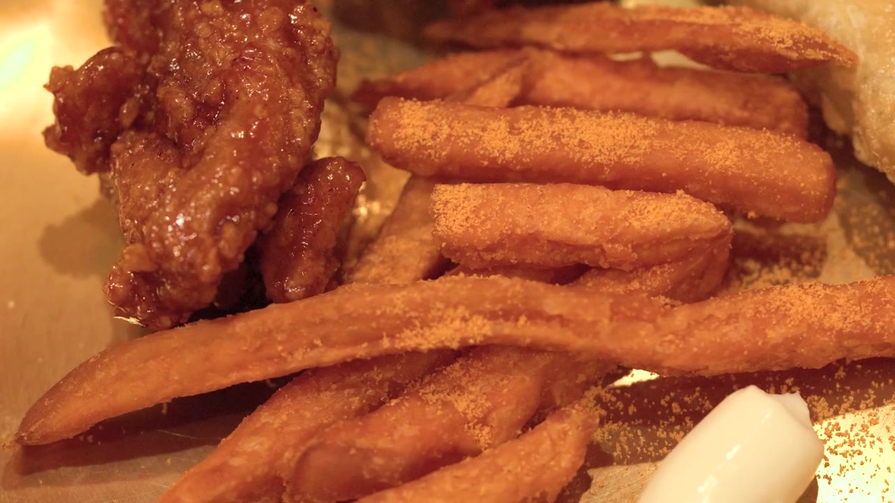 Toma macro de pollo picante glaseado, patatas fritas sazonadas y empanadillas en un plato de latón