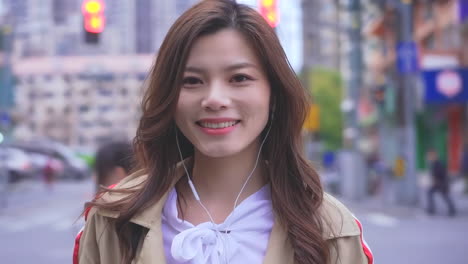 portrait beautiful happy young woman who listens to music with headphones on the background of the evening city street