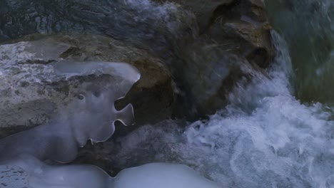 mountain creek with crystal clear icy water gently flowing through ancient rocks, close-up slow motion