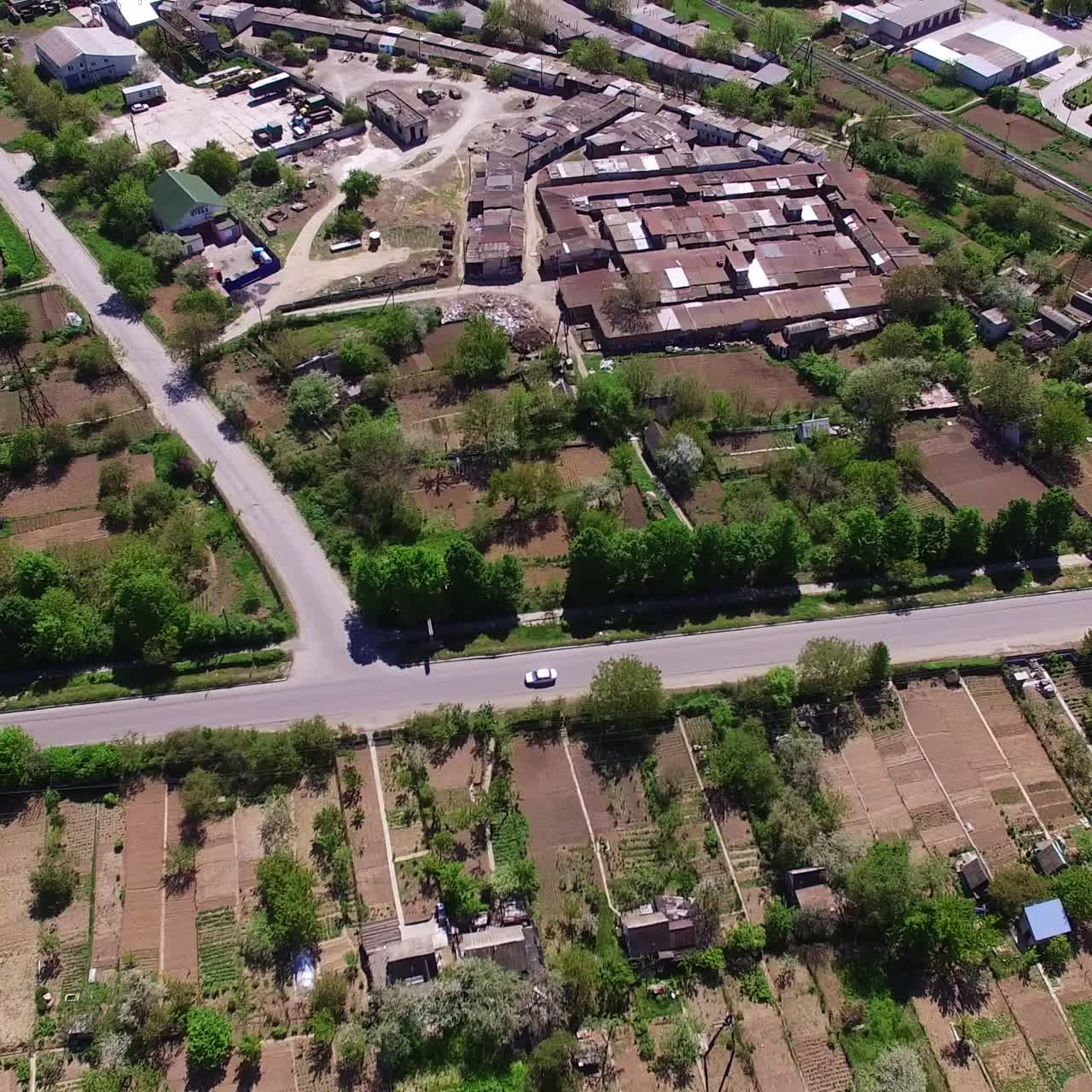Footage over the green forest, industrial zone and city residential area. Aerial perspective on the urban territory on sunny daytime