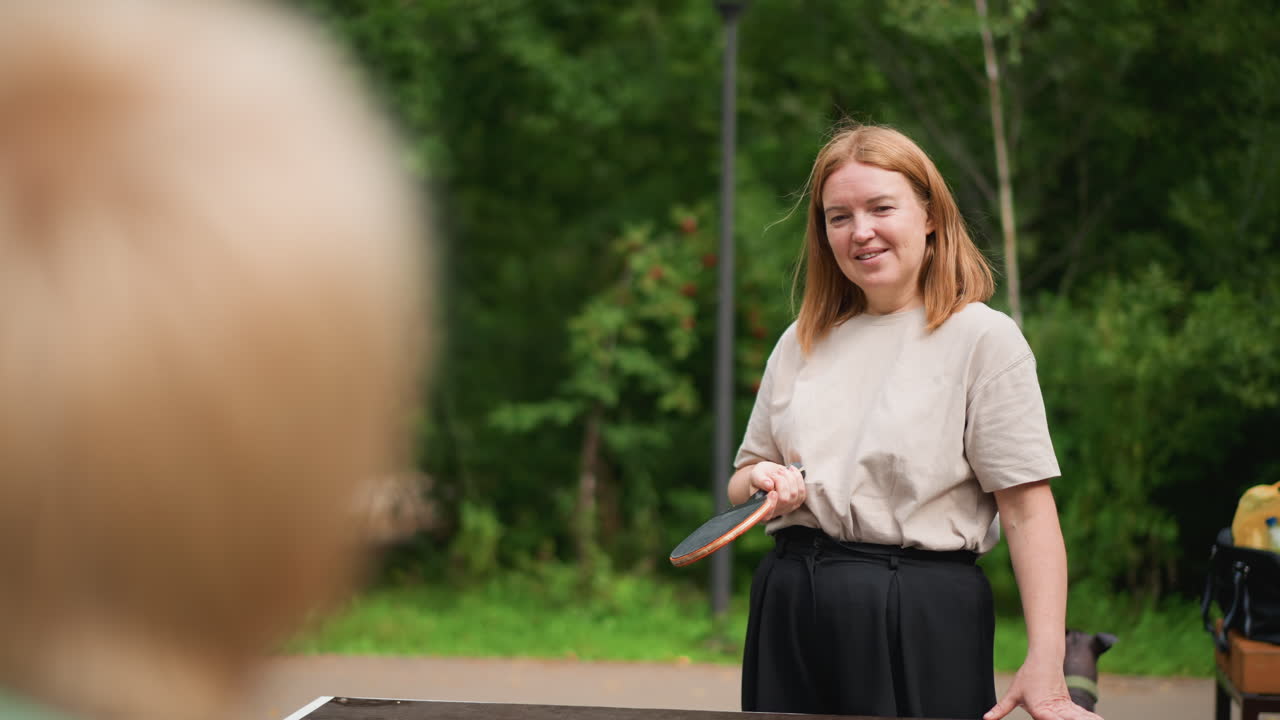 Outdoor Table Tennis Coaching With Caucasian Woman Instructing Child At Park, Paddle Demonstration, Patient Smile, Guidance And Playful Teaching Atmosphere Among Trees And Summer Warmth