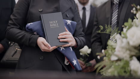 manos, bandera estadounidense y la biblia con una persona