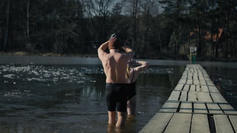 Rear-view-of-caucasian-man-and-woman-going-into-a-frozen-lake.