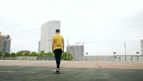 Young-Attractive-Trendy-Man-skateboarding-fast-under-a-solar-panel-on-a-morning-sunny-day-with-an-urban-city-background-in-slow-motion