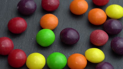 colored fruit candies rotate on a black background, colored marco sweets