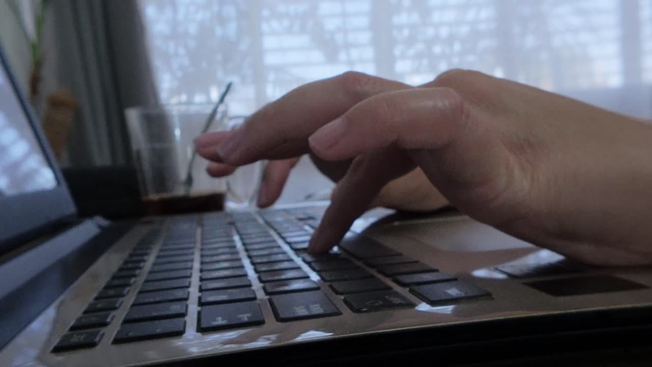 Side view of a woman demonstrating digital literacy skills by proficiently typing on a laptop.