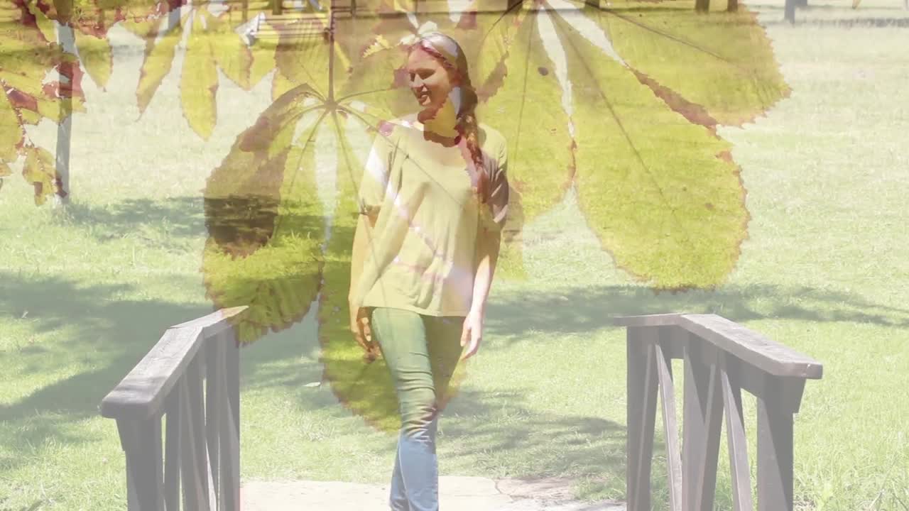 композитное видео листьев, висящих на дереве против кавказской женщины, идущей по мосту в саду