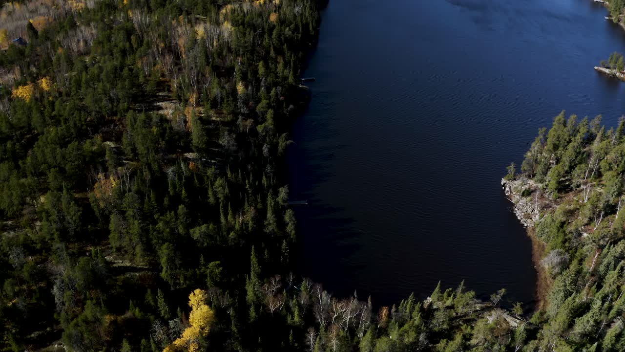 Carrellata aerea in avanti di laghi blu immersi in una foresta boreale nell'idilliaco scudo canadese