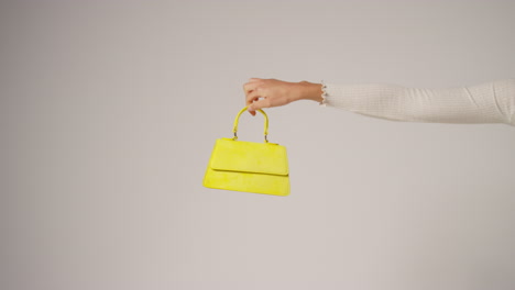 close up of female social media influencer producing user generated content holding out yellow fashion handbag