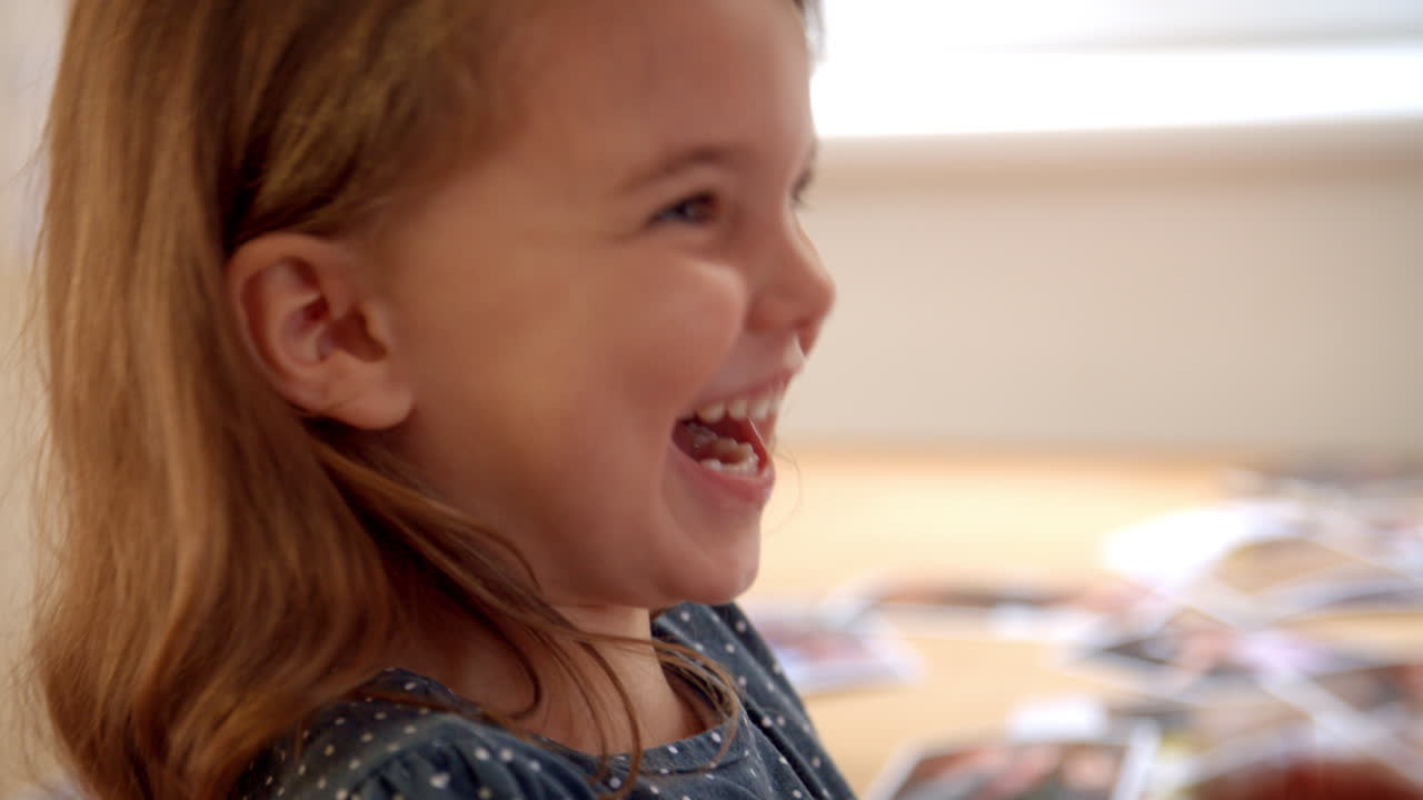 Daughter Sitting On Mother's Lap At Home And Laughing