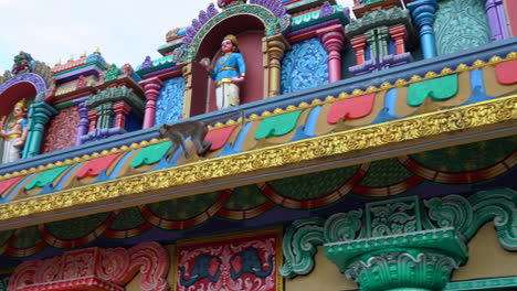 Playful-monkey-running-across-the-roof-of-a-colorful-temple-at-the-Batu-Caves-in-Kuala-Lumpur,-Malaysia