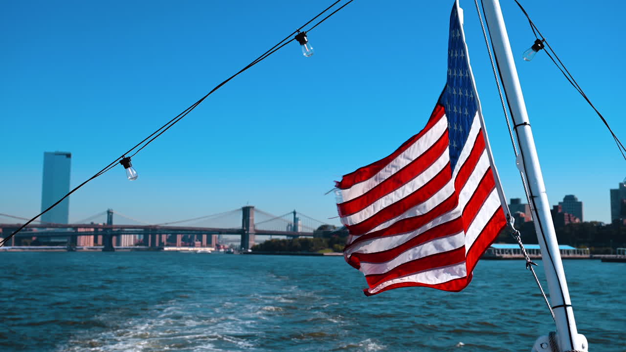 Bandiera americana appesa a una barca che naviga sull'East River. Il Manhattan Bridge e il Brooklyn Bridge sullo sfondo