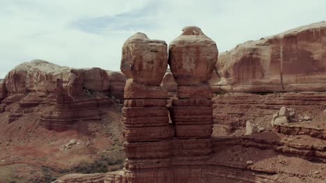 navajo twins standing rock formations on red sandstone cliffs of bluff, utah - aerial orbit