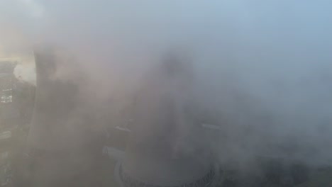 aerial dolly left view of atmospheric power station cooling towers smoke steam emissions global warming