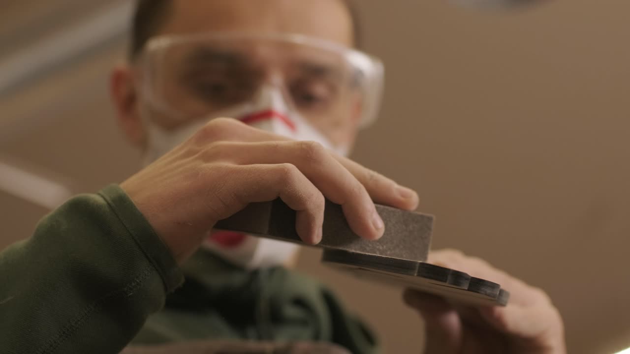 A carpenter is grinding a piece of wood, a plywood product made on a CNC laser machine using sandpaper