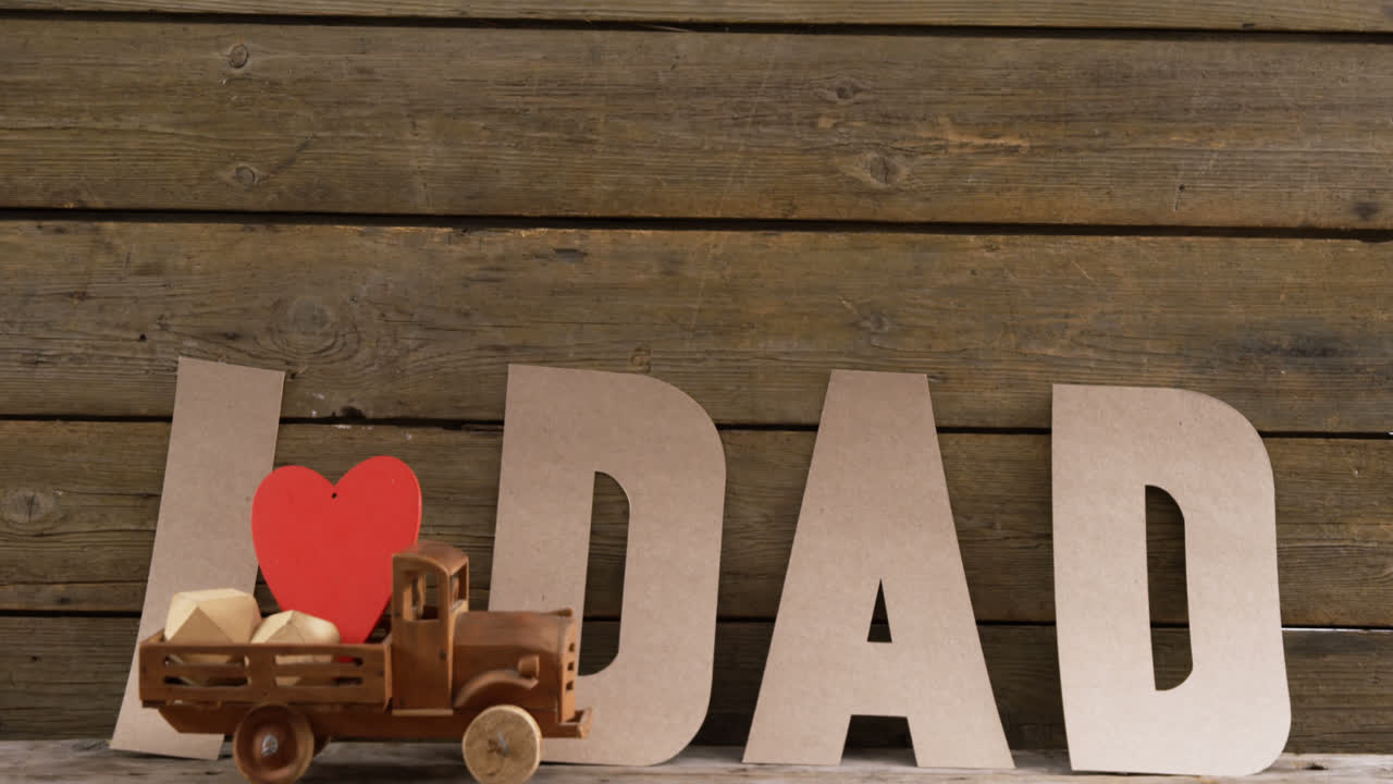 camión de juguete con corazón rojo contra el texto papá