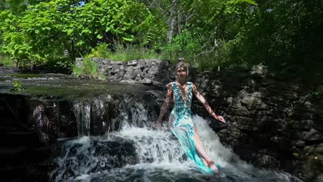 young women sitting on a small waterfall in a swimsuit on a summer day slow-motion panning shot