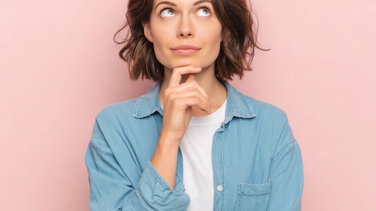 Una donna pensierosa contempla con un'espressione curiosa su uno sfondo rosa tenue, in una serie di accattivanti inquadrature del suo riflesso.