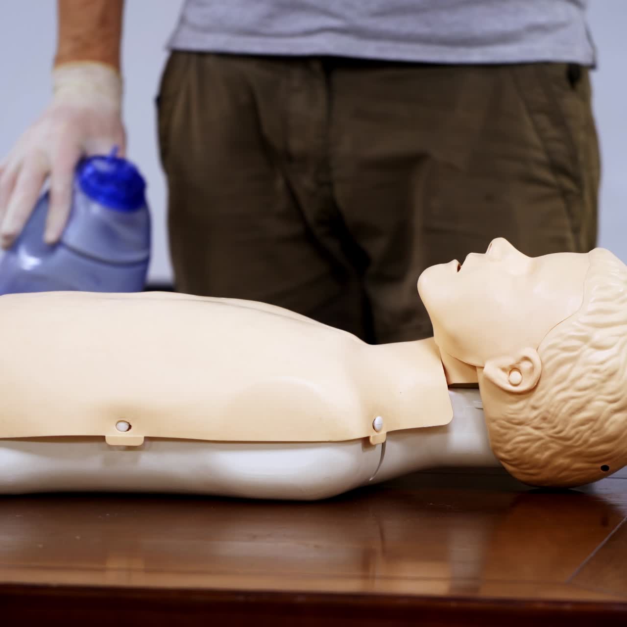 Instructor near mannequin in medical center. Trainer demonstrating cpr procedure on a medical doll. Healthcare and education concept