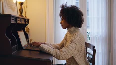 una mujer seria trabaja en una computadora en una mesa vintage.