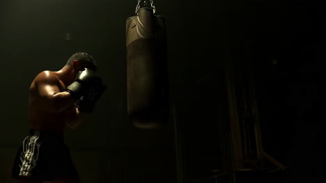 boxer training with punching bag in a dimly lit gym