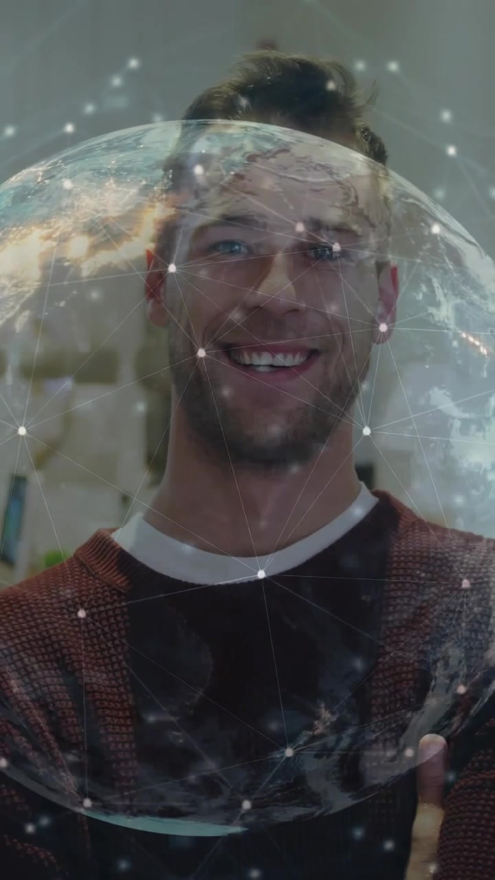 Video verticale: Uomo in piedi a braccia conserte che ruota un globo su nodi, rivelando un volto sorridente per la tecnologia.