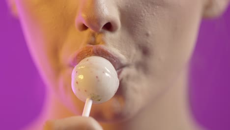 una mujer caucásica linda chupa una piruleta blanca, concepto de sexo oral, rostro de primer plano