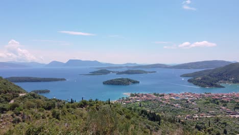 A-couple-stands-on-a-hill-overlooking-the-coastal-sights-of-Nidri,-Greece