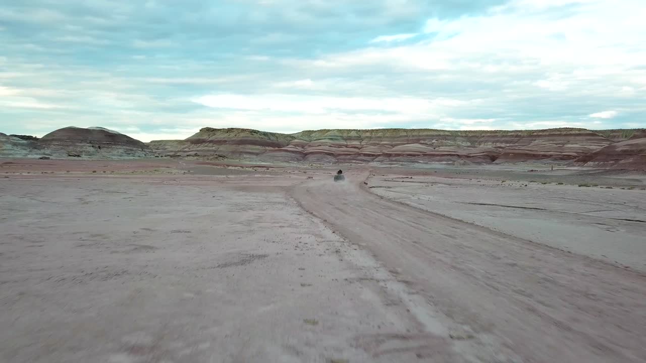 seguimiento de la vista aérea del hombre conduciendo quad atv en el paisaje seco del desierto de utah, dramática escena apocalíptica