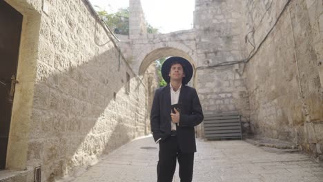 front portrait of orthodox jewish man with book wandering through western wall in jerusalem. medium shot