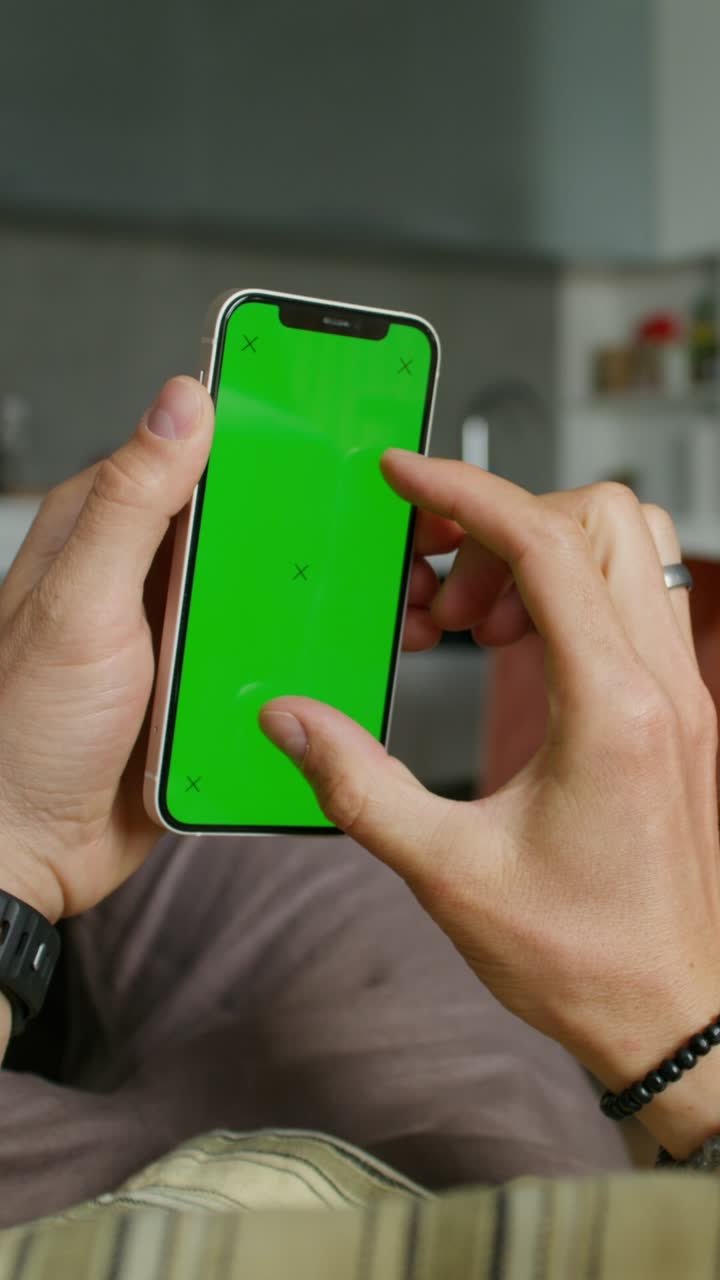 persona usando un teléfono inteligente con una pantalla verde en una cocina.