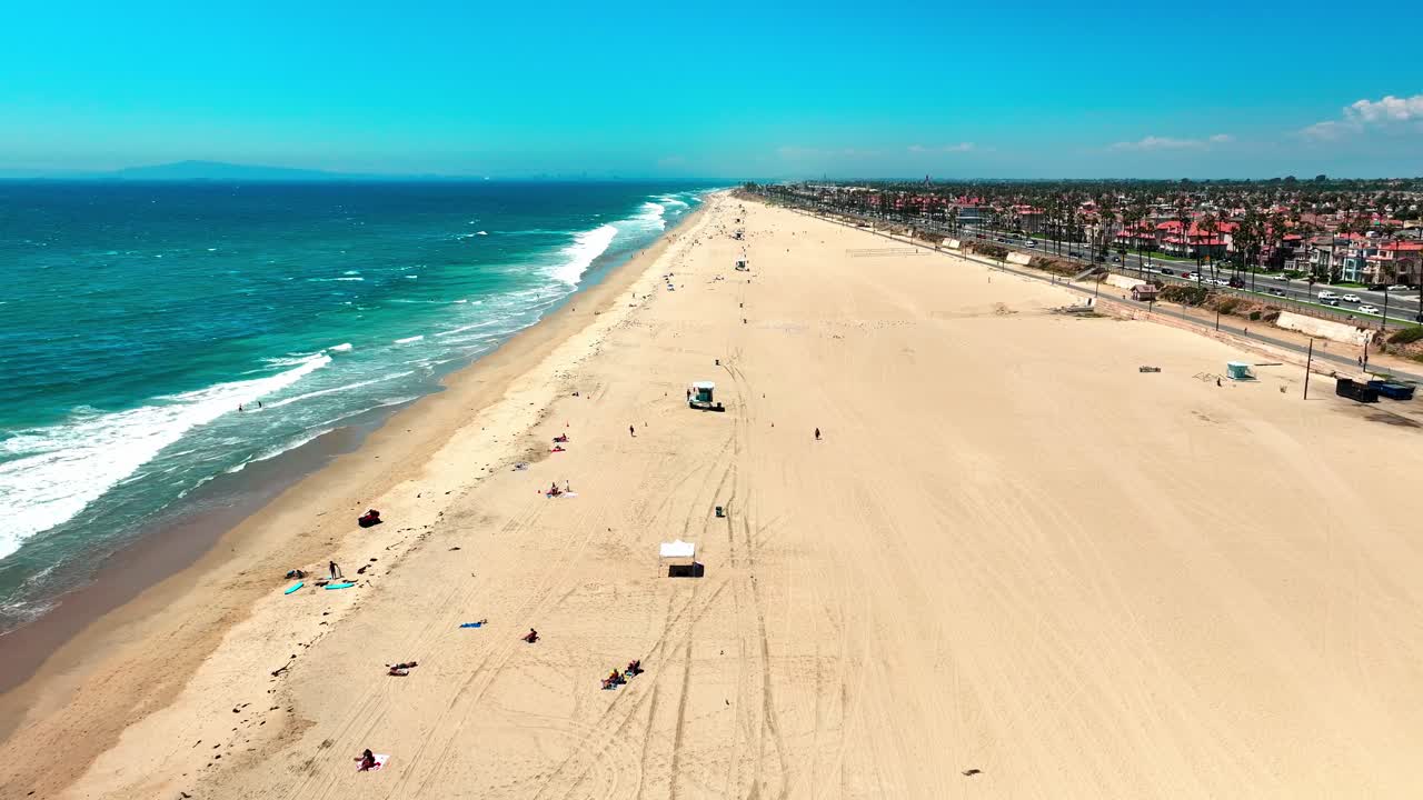 drone volando sobre huntington beach con casi ninguna gente y algunas grandes olas rompiendo en la orilla