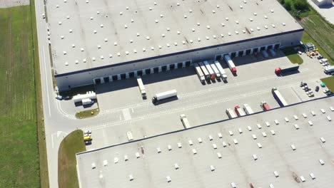 aerial shot of industrial warehouse loading dock where many truck with semi trailers load merchandise