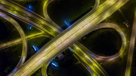 hyperlapse timelapse zoom out of night city traffic on 4-way stop street intersection circle roundabout in metropolis. 4k uhd horizontal aerial view