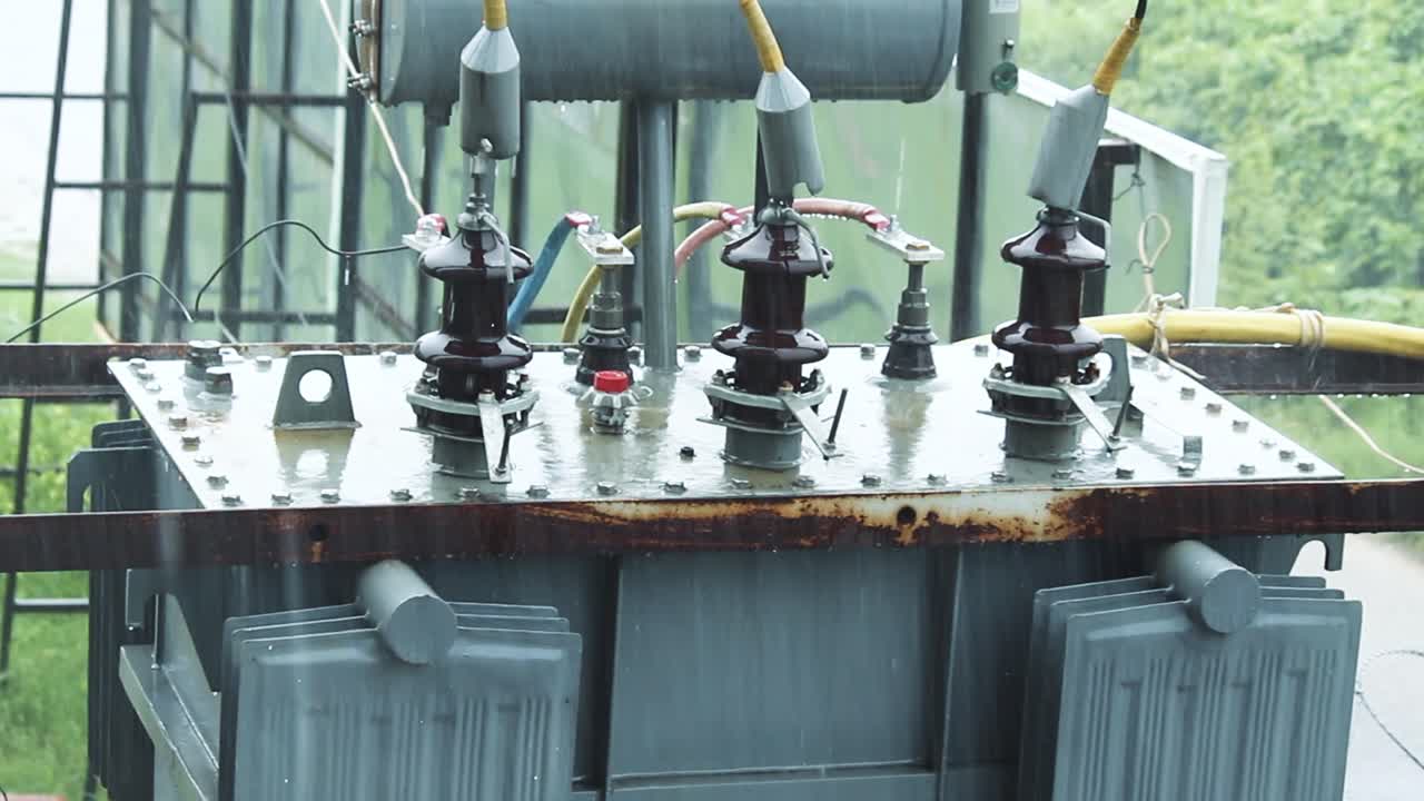 Raindrops fall on outdoor transformer during rain shower. Moody, industrial and atmospheric clip ideal for weather, power or texture-focused projects