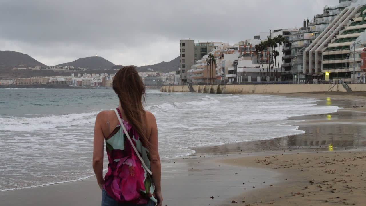 кинематографический снимок женщины на восходе солнца, любующейся пляжем лас-кантерас