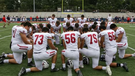 a group of football players engaged in a pre-game prayer, demonstrating unity and team spirit on the field before the big match