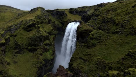 handheld shot of a mighty big waterfall with a large fall of the water, hidden in between the mountains