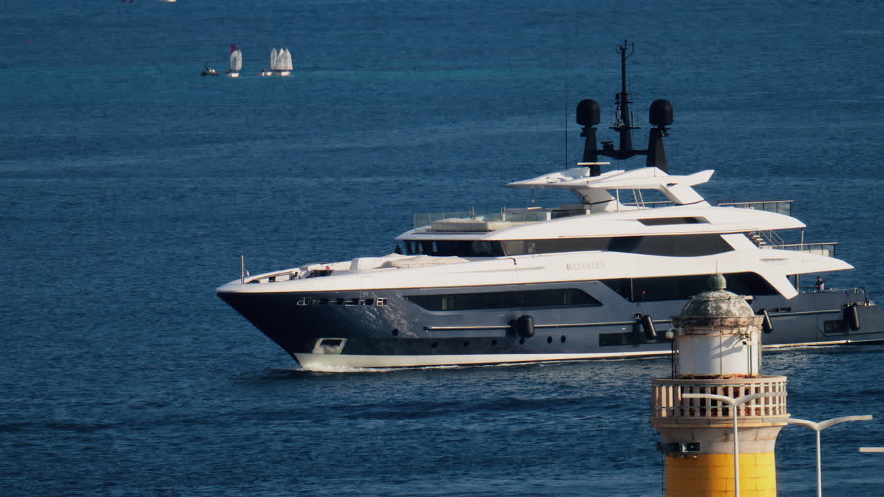 Cannes, France - March 16, 2025: A white boat moving on the sea, near a lighthouse, on a sunny day