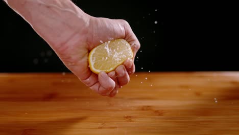 person hand squeezing fresh lemon with squirting juices, super slow motion