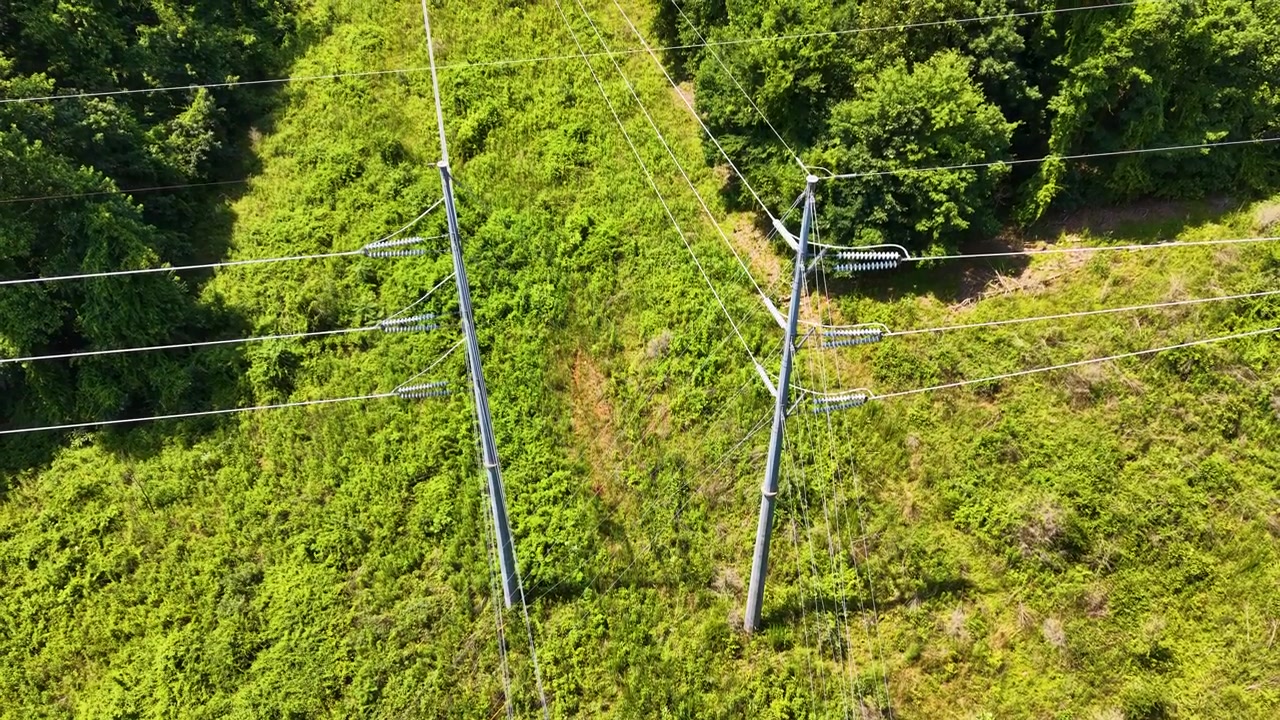 High-voltage transmission corridor near Chattanooga, Tennessee, United States, revealing steel monopoles, overhead conductors, managed utility easement and deciduous woodland, aerial view.