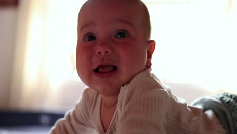 baby girl at 4 months on laying on tummy and crying towards camera - close up on face